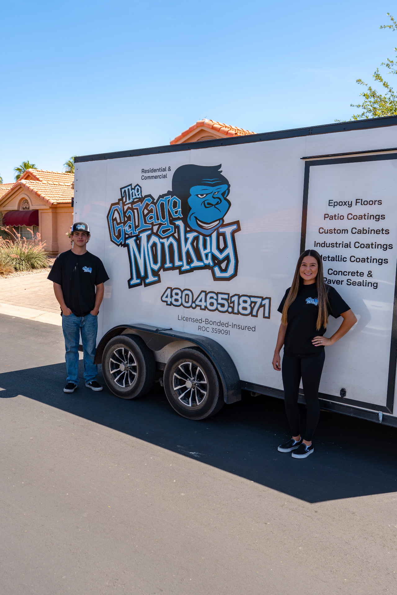 The Garage Monkey husband and wife team standing with their work trailer